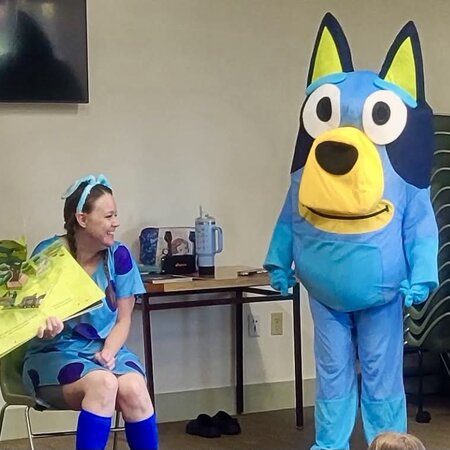 Storyteller reading a picture book with the Bluey character at a Utah story time event