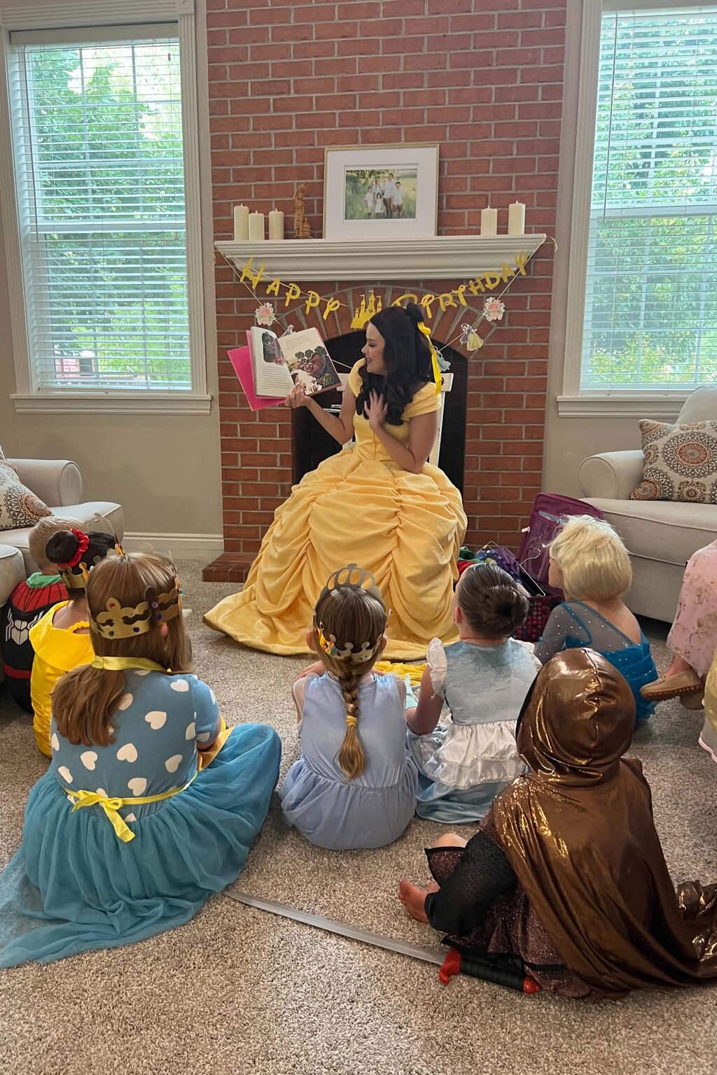 Princess character reading a storybook aloud to a group of children during story time