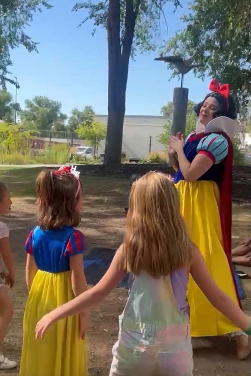 Princess character leading children in music and movement at an outdoor community event in Utah